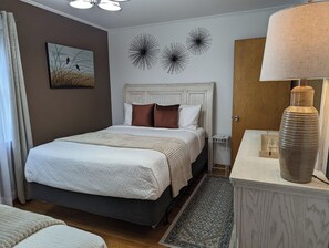 A bedroom with a bed, a nightstand, a lamp, and wall art. - Harriet House in Potsdam (Potsdam)