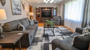 Uma sala de estar moderna com um sofá, poltronas, uma mesa de centro e uma televisão.