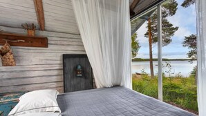 Un dormitorio con una cama, cabecera de madera, un farol y vistas a un lago.