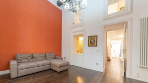 Amplia sala de estar con sofá modular, piso de madera, una araña y vista al piso superior.