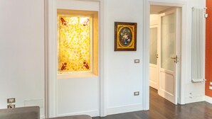 Un pasillo con una puerta blanca, un cuadro enmarcado y un radiador.