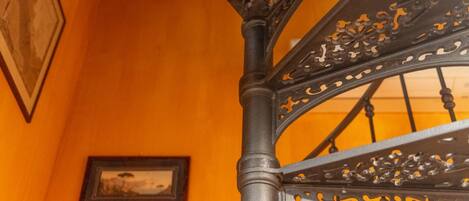 A spiral staircase with ornate metal railings and a picture frame on the wall.