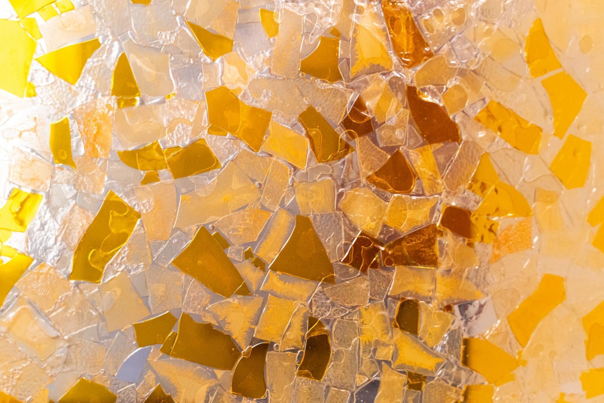 Een mozaïek van glazen stukken in verschillende tinten geel en bruin.