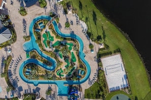 An aerial view of a resort with a large pool area, multiple water slides, and a beach section. - New Home at Storey Lake 8 Bedrooms and 5 Bathrooms (Kissimmee)