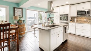 Une cuisine moderne avec des meubles blancs, un îlot central et une vue sur l’extérieur.