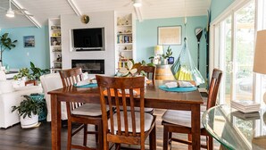 Un salon spacieux avec une table à manger en bois, des sièges confortables, une cheminée et un téléviseur.