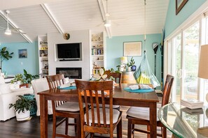 A spacious living room with a wooden dining table, comfortable seating, a fireplace, and a television.