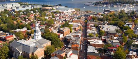 An aerial view of a coastal town with a prominent church, a marina, and a bridge in the background.