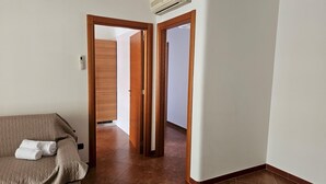 A hotel room with a bed, a wooden wardrobe, and a hallway leading to another room. - Casa Calette in Monopoli (Monopoli)