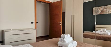 A hotel room with a bed, a wardrobe, a mirror, and a painting on the wall.