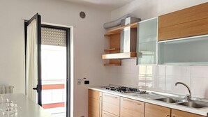 A modern kitchen with wooden cabinets, a stainless steel sink, and a gas stove. - Casa Calette in Monopoli (Monopoli)
