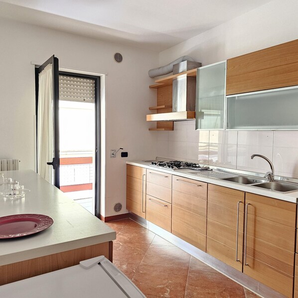A modern kitchen with wooden cabinets, a stainless steel sink, and a gas stove.
