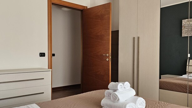 A hotel room with a bed, a wardrobe, a mirror, and a door. - Casa Calette in Monopoli (Monopoli)