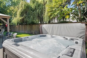 A hot tub in a backyard with a wooden deck, chairs, and a pergola. - McMinnvile Suburban Oasis, Pet Friendly, Hot Tub, Epic Covered Patio, 1.5 Miles 2 Museum & Waterpark (McMinnville)