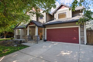 A two-story house with a red garage door, stone pillars, and a front porch.