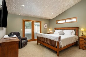 A bedroom with a bed, a desk, a chair, a window, and a ceiling with recessed lighting.