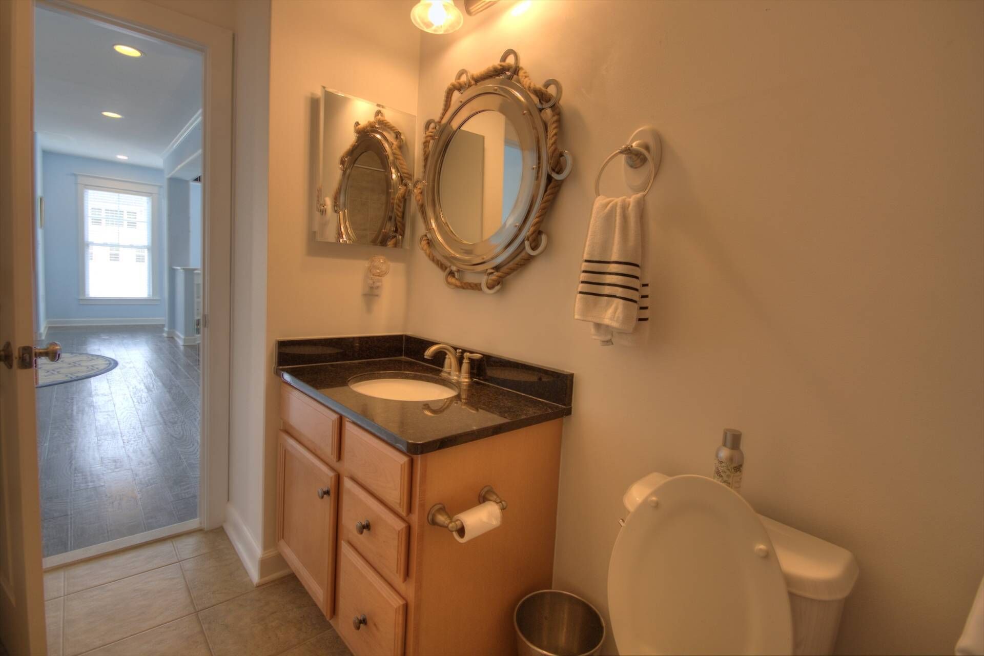 A bathroom with a vanity, two mirrors, a toilet, and a towel rack.