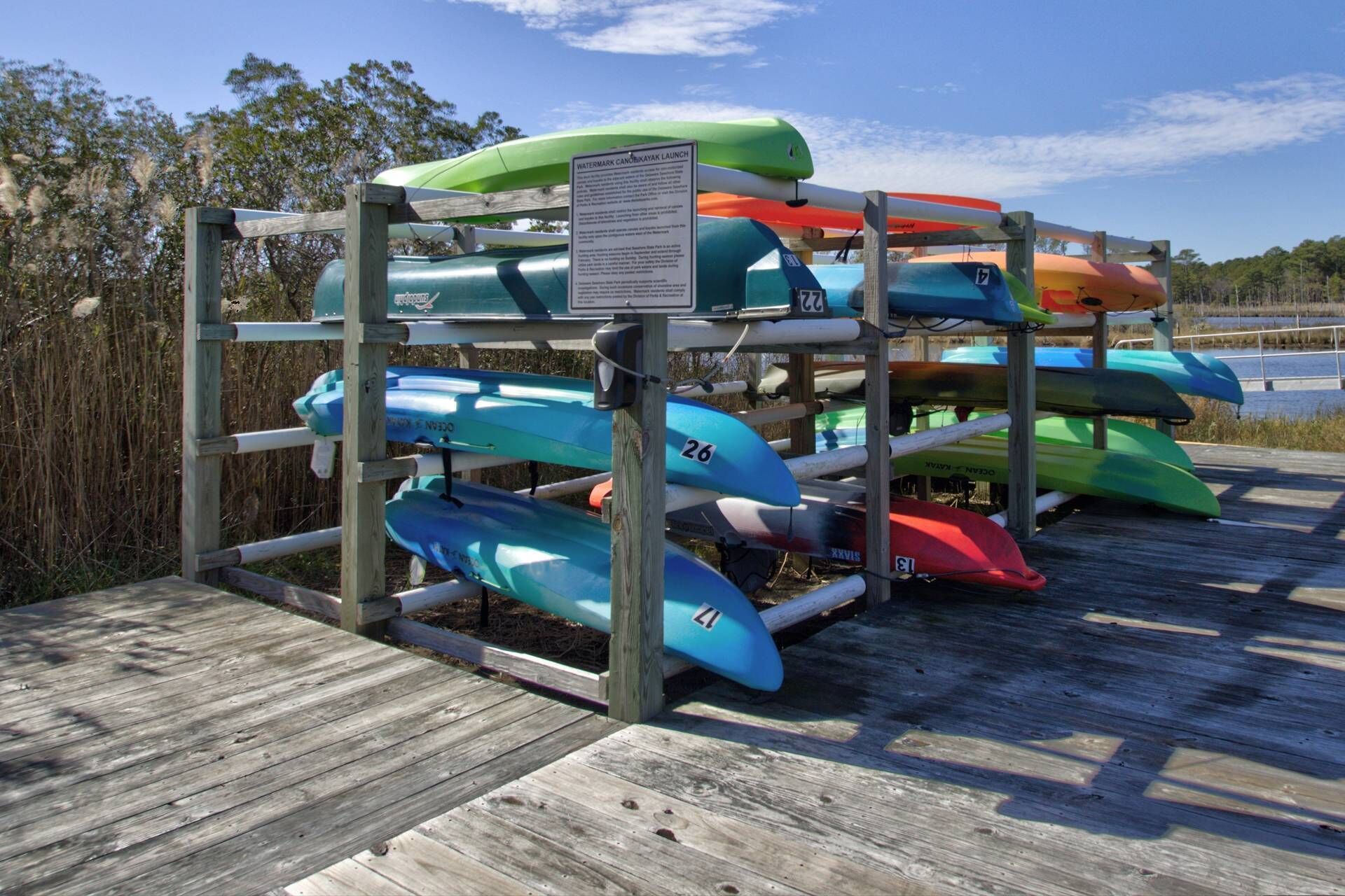 Une jetée en bois avec un support où sont rangés plusieurs kayaks.