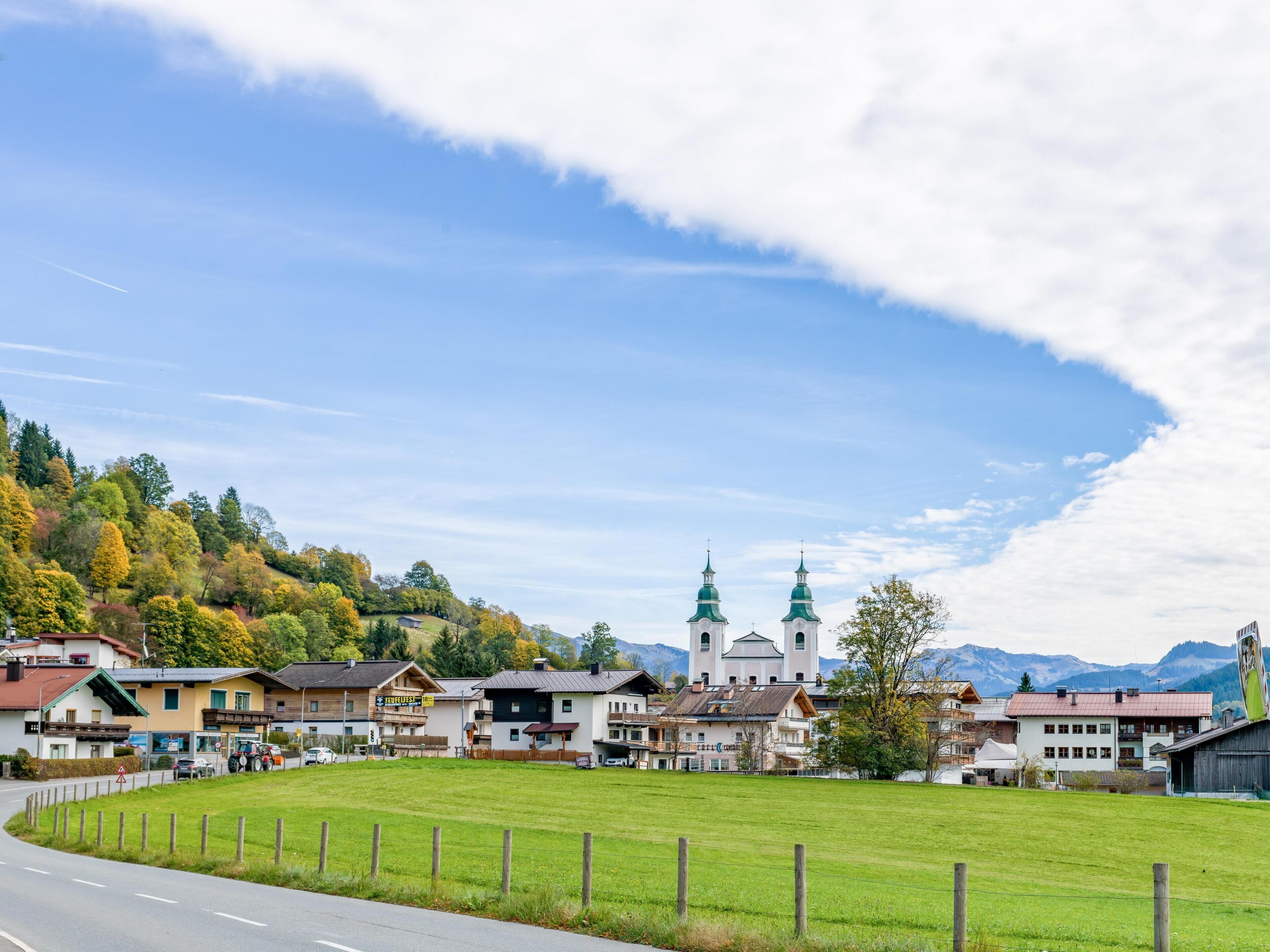 A town with a prominent church featuring two green spires, surrounded by residential buildings and a large green field.