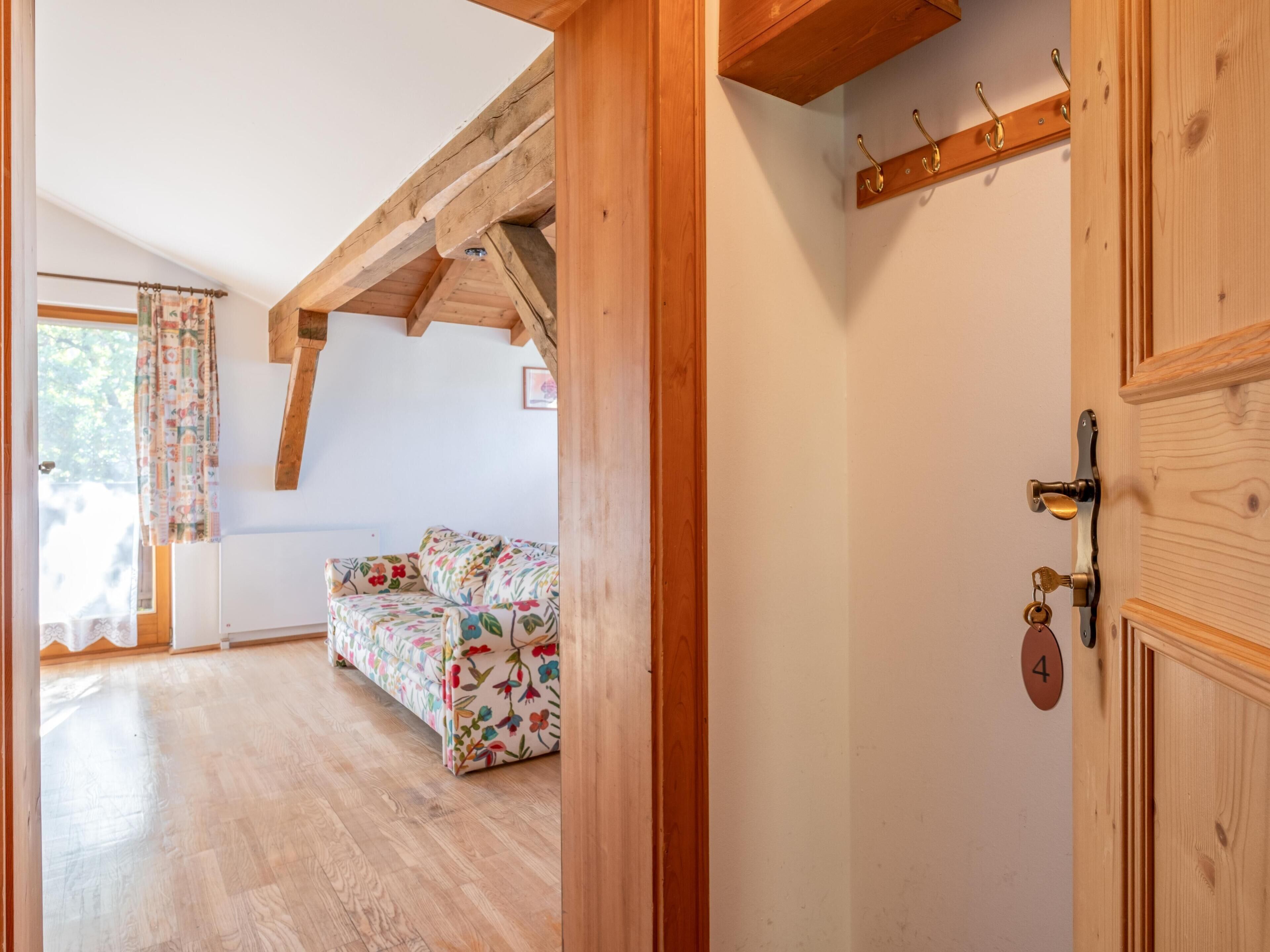 Een kamer met houten balken, een bloemenbank en een deur met nummerbord.