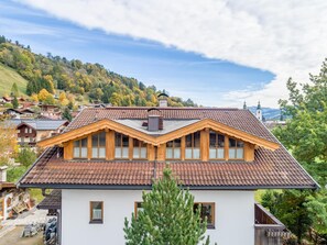 Une maison à deux étages, dotée d’un toit en pente, d’un revêtement extérieur en bois et de nombreuses fenêtres.