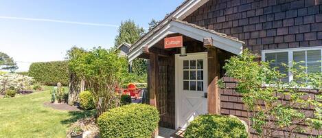 A cottage with a wooden exterior, a white door, and a sign that reads "Cottage."