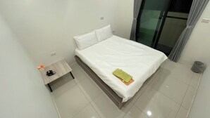 Ein sauberes, modernes Hotelzimmer mit einem großen Bett, einem kleinen Nachttisch und Blick nach draußen durch eine Glastür.