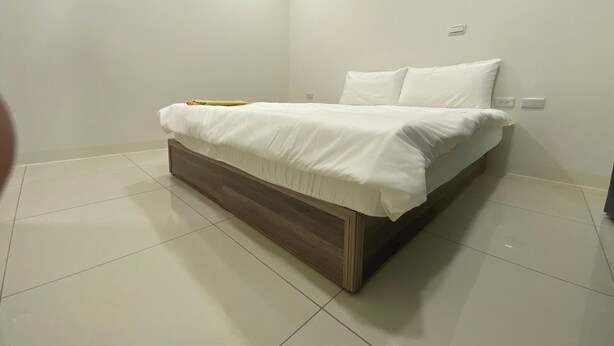 Ein modernes Schlafzimmer mit Bett, weißen Wänden und Fliesenboden.