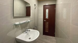 Ein modernes Badezimmer mit einem weißen Waschbecken, einer Glasablage, einer Holztür und einem Spiegel an der Wand.