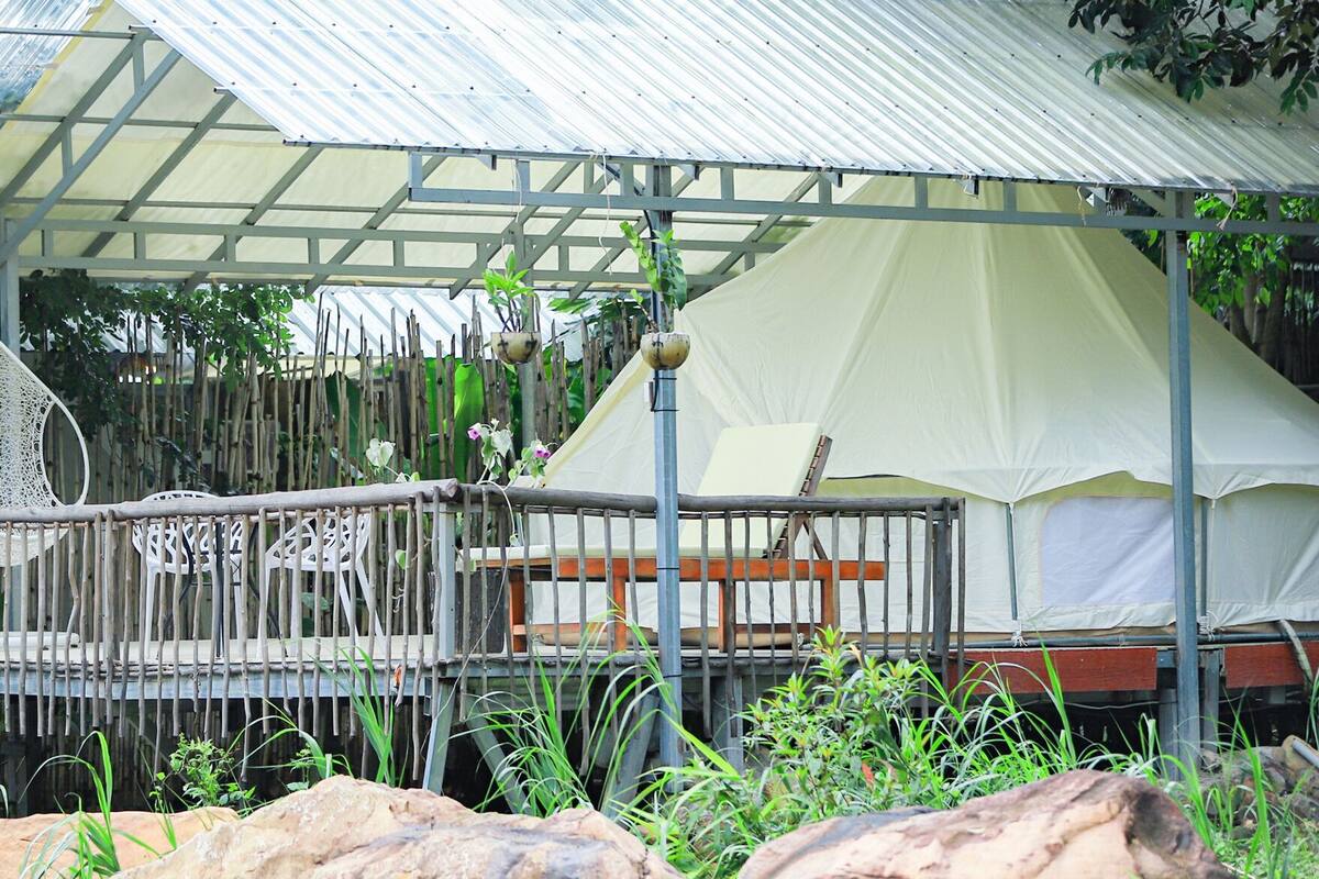 A covered outdoor area with a metal roof, a white tent, and a wooden deck with railings.