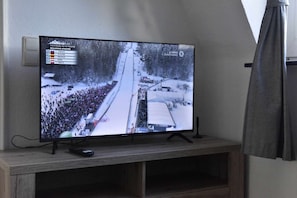 A television displaying a snowy scene with a crowd and a building labeled 'LIUBNO 1. DURCHGANG'.