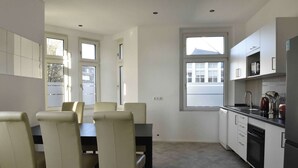 Une cuisine moderne avec des meubles blancs, une table à manger avec des chaises et une fenêtre.