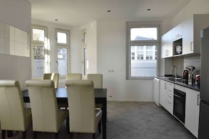 A modern kitchen with white cabinets, a dining table with chairs, and a window.