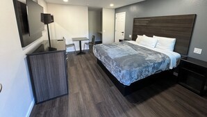 Een moderne hotelkamer met een groot bed, een bureau, een stoel en een aan de muur bevestigde televisie.