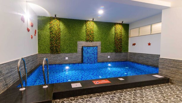A swimming pool with a blue tiled floor, surrounded by walls with green vertical gardens and a tiled border. - Lotus & Orchid Villas by Ramnath Homes (Alto de Porvorim)
