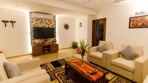 A living room with a sofa, armchairs, a coffee table, a TV, and a ceiling fan. - Lotus & Orchid Villas by Ramnath Homes (Alto de Porvorim)