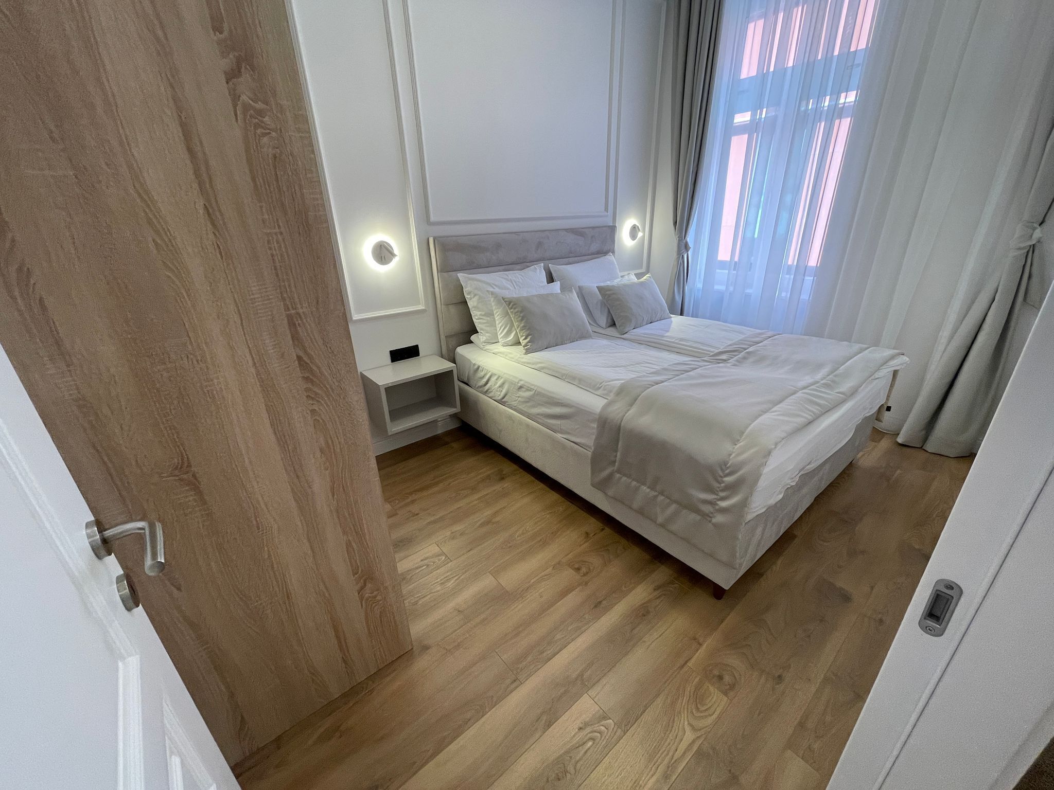 A bedroom with a bed, bedside tables, and a wooden floor.