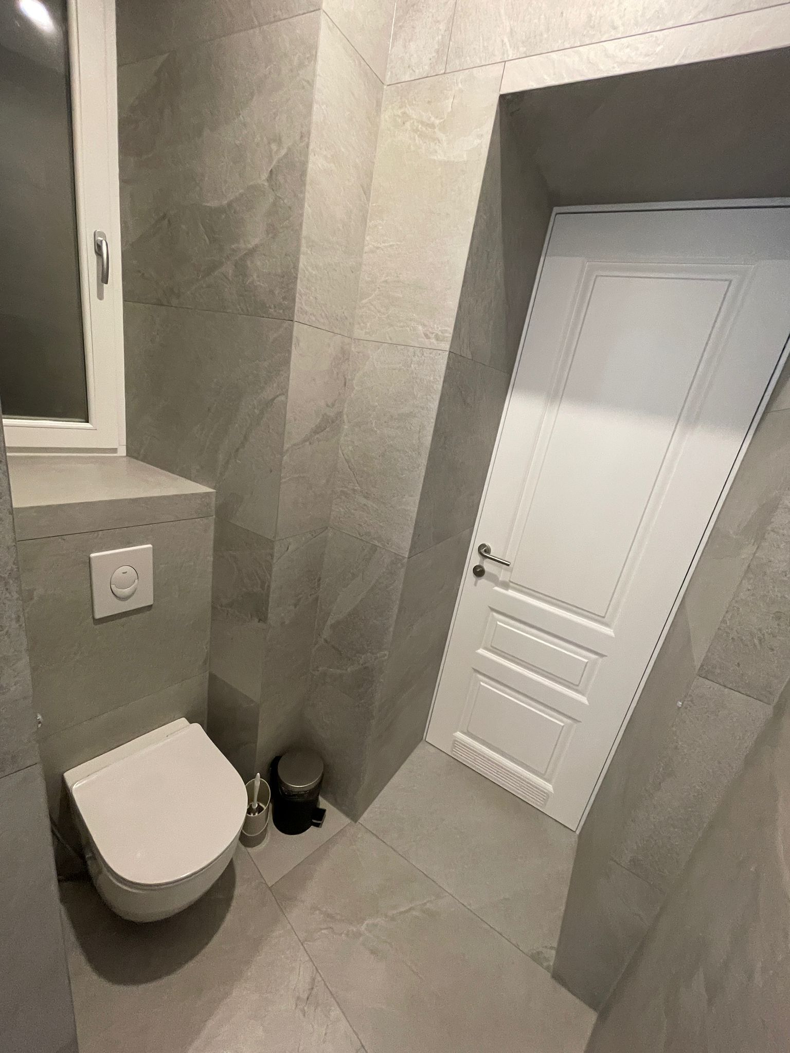 Ein kleines Badezimmer mit Toilette, Waschbecken und einer Tür.