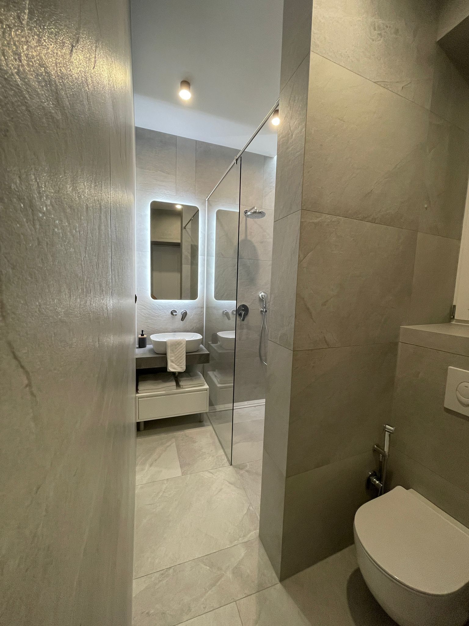 A modern bathroom with a glass-enclosed shower, a white sink, and a toilet.