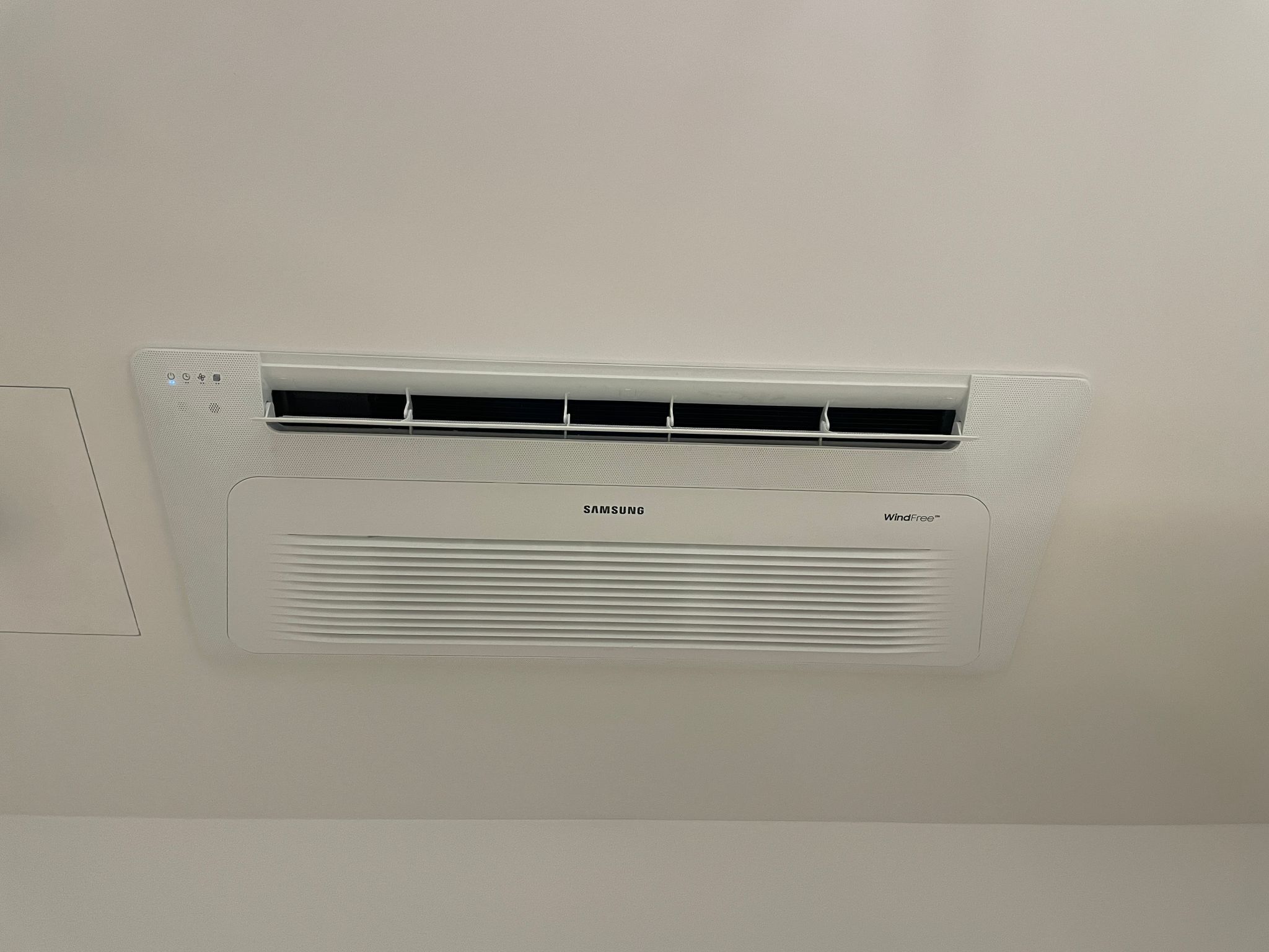 A wall-mounted air conditioning unit with a control panel and a digital display.