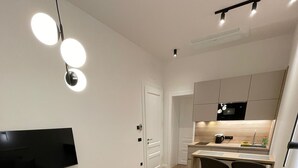 Una sala de estar moderna con un sofá color beige, una mesa de centro redonda y un televisor de pantalla plana montado en la pared.