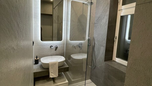 A modern bathroom with a glass-enclosed shower, two sinks, and a large mirror. - Central Apartments Sarajevo (Sarajevo)