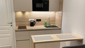 Cocina compacta con microondas, lavamanos y una pequeña mesa con dos sillas.