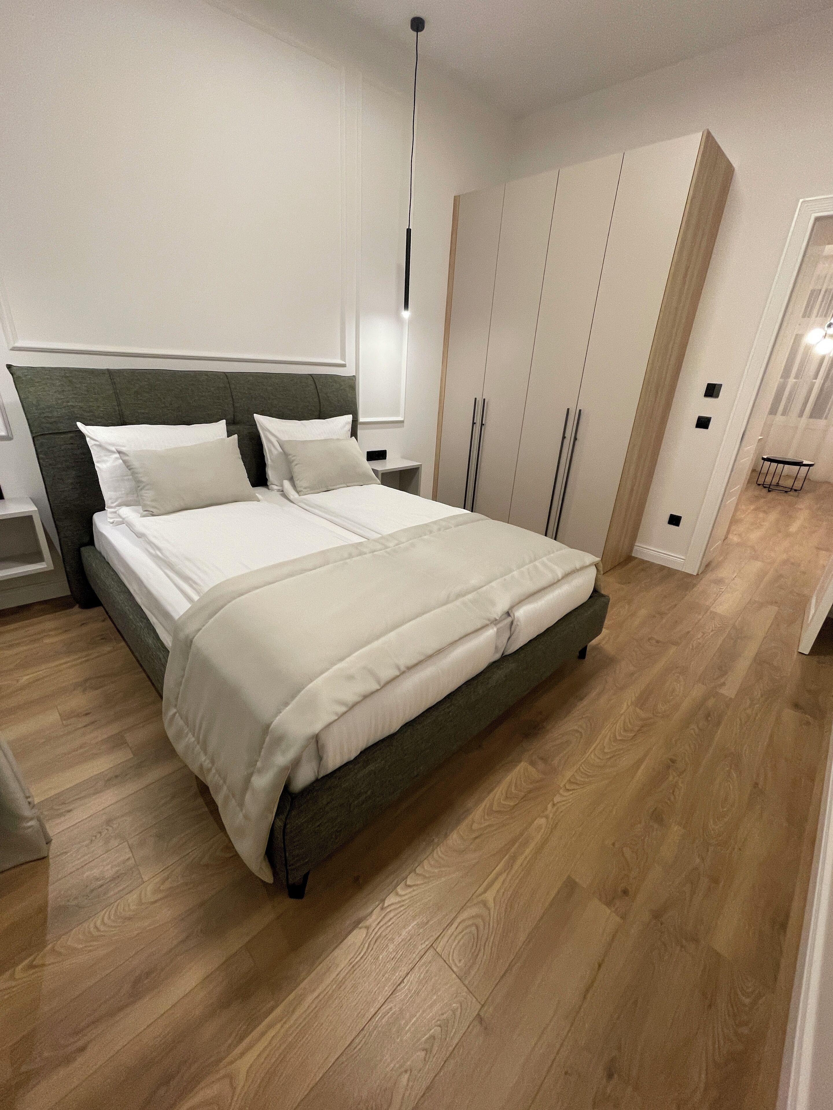 Une chambre moderne avec un grand lit, un plancher en bois et des armoires encastrées.