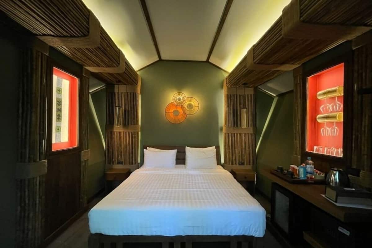 A room with a bed, bedside tables, a wall-mounted light fixture, and a red illuminated sign.