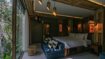 Ein Schlafzimmer mit einem großen Bett, einer Bank und einem Fenster mit Blick auf Grünflächen.
