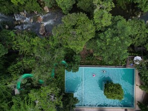 An aerial view of a swimming pool surrounded by dense greenery, with a visible water slide and a person swimming. - Nam Pien Yorla Pa (Parkngum)