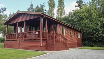 A wooden cabin with a porch and a staircase leading to the entrance.