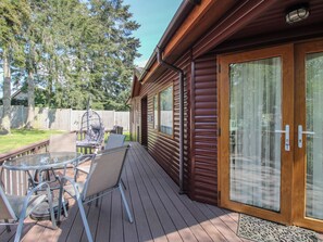 A wooden deck with a glass door, outdoor furniture, and a swing chair. - Foxglove (Leominster)