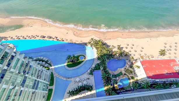 An aerial view of a resort with a pool area, beach, and a building with multiple floors. - Stunning Beach Front Condo in Peninsula Tower 1! 3BD Condo for rent in North Hot (Puerto Vallarta)